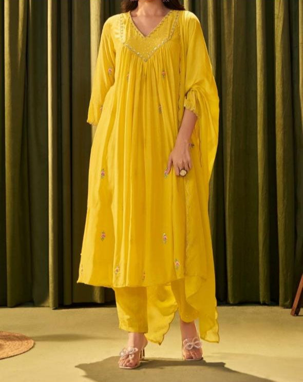 Person wearing a yellow outfit against a green curtain background