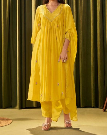 Person wearing a yellow outfit against a green curtain background